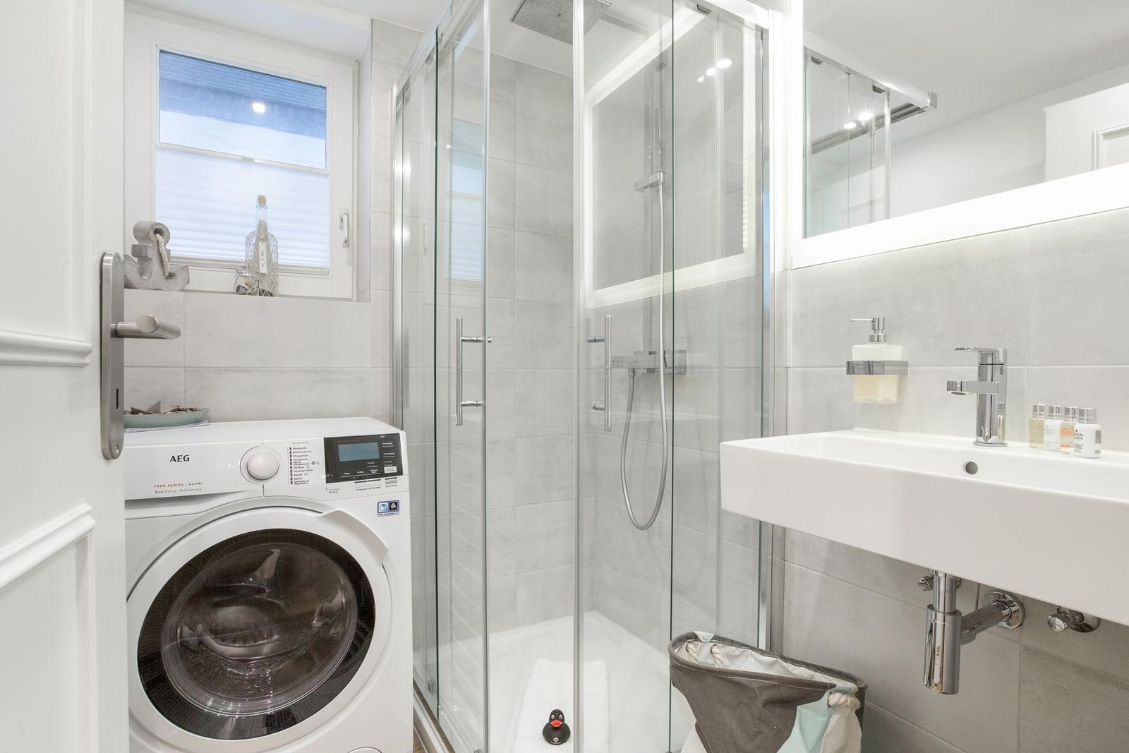 Bathroom with shower, washing machine, and sink