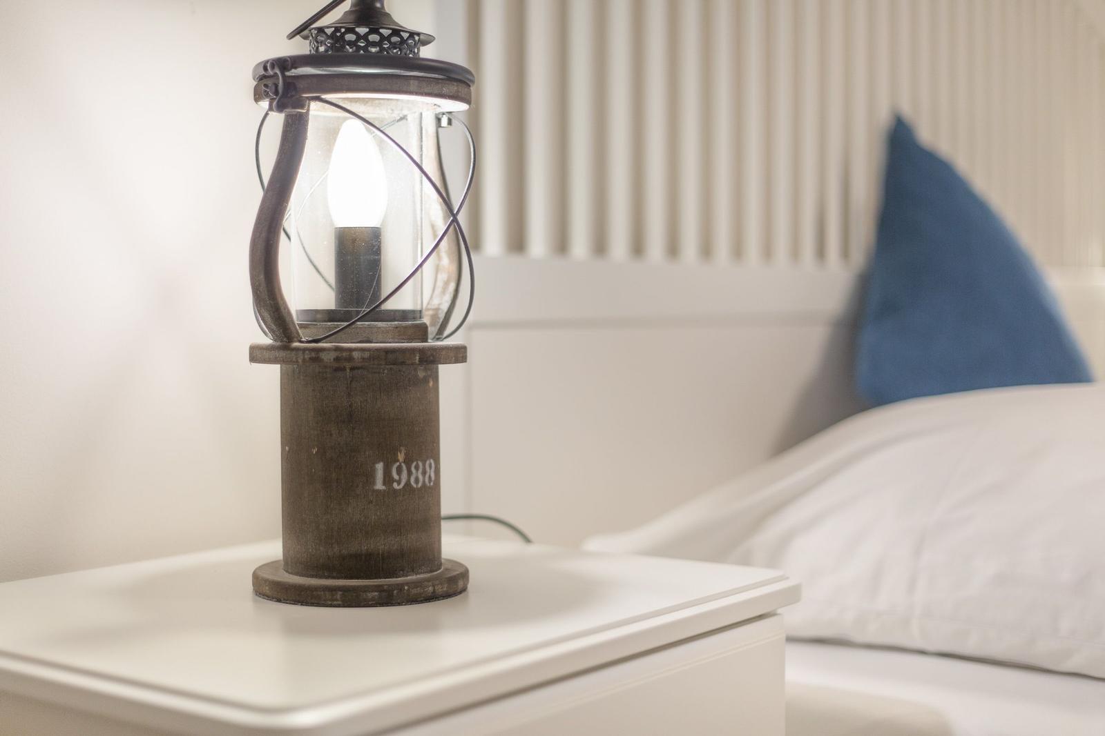 Lamp on nightstand next to bed with pillow