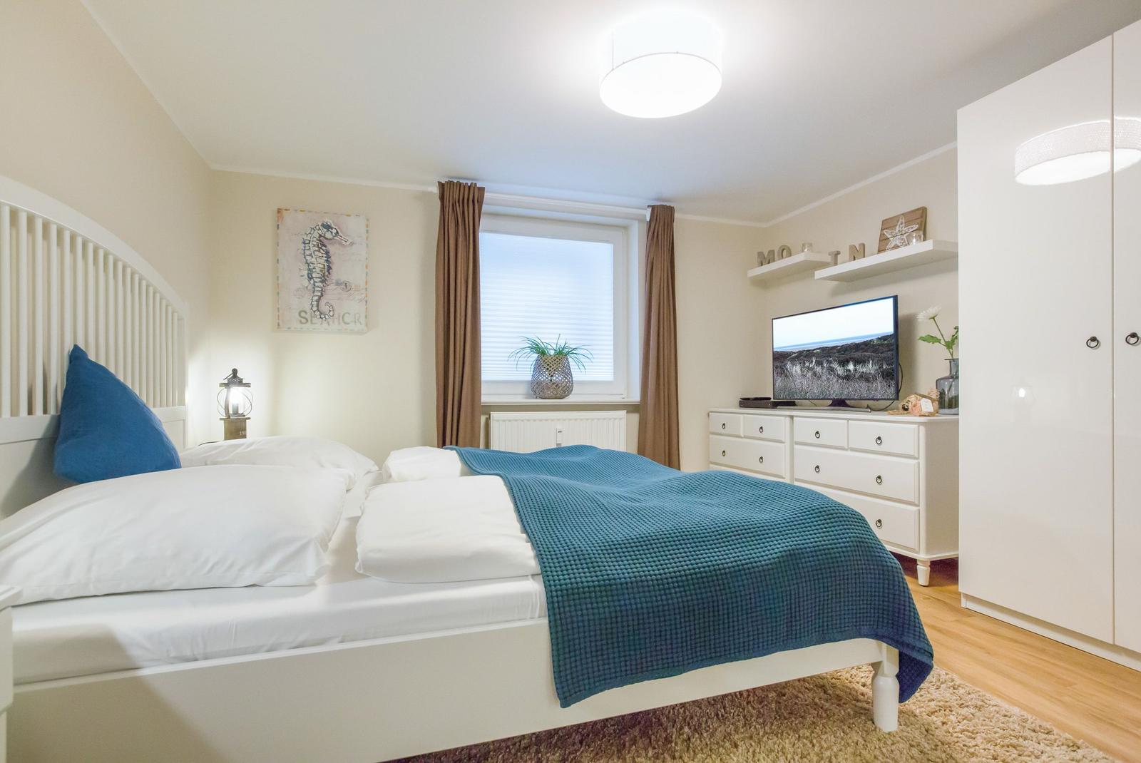 Bedroom with bed, TV, and wardrobe.