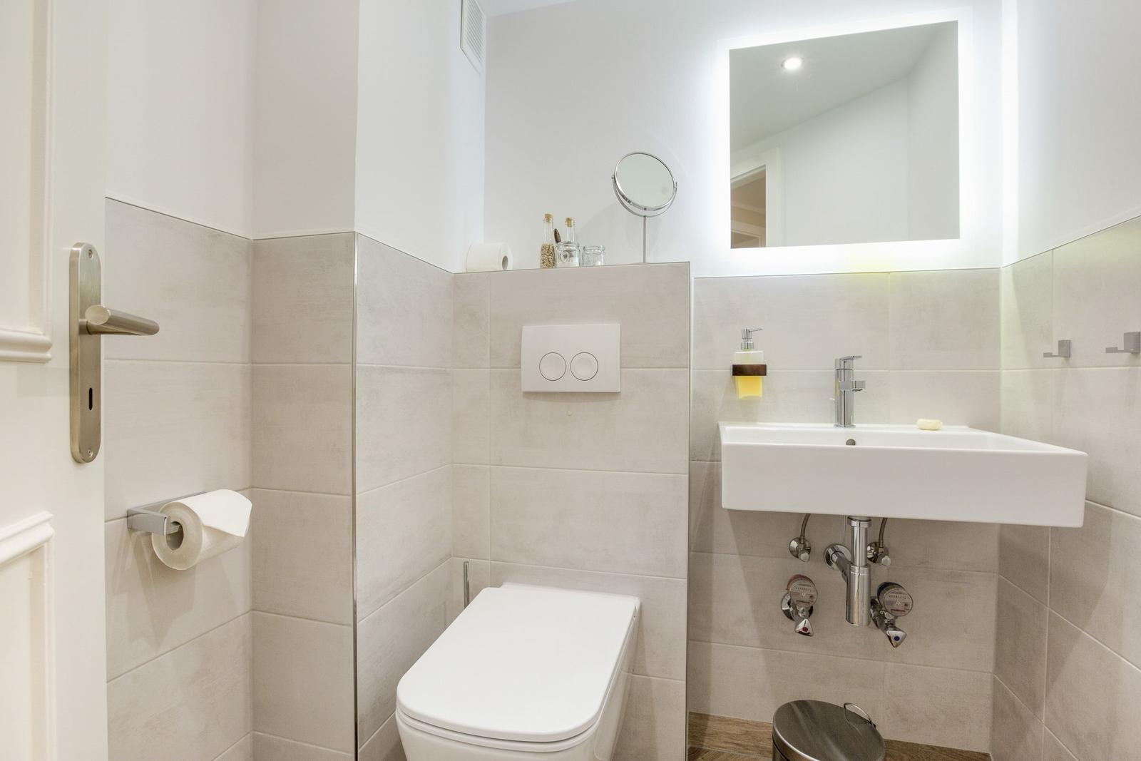 Bathroom with toilet, sink, and lit mirror