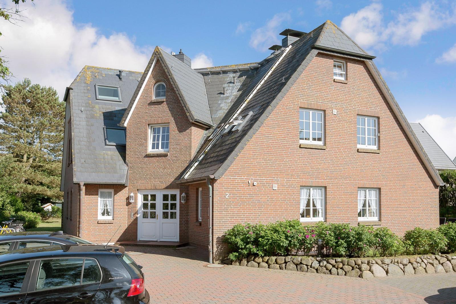 Two-story brick house with gray roof and white front door.