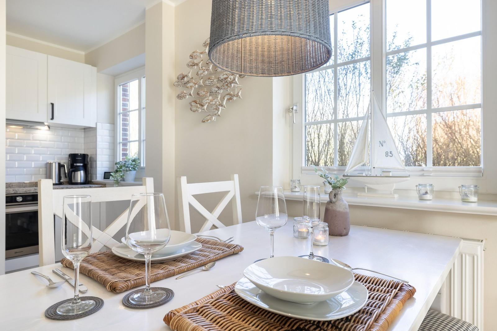 Dining table for two, white table, chairs, window with sailboat.
