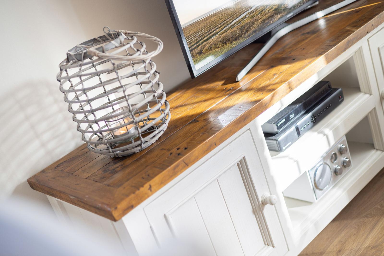 TV stand with wooden top, television, and decorative lantern.