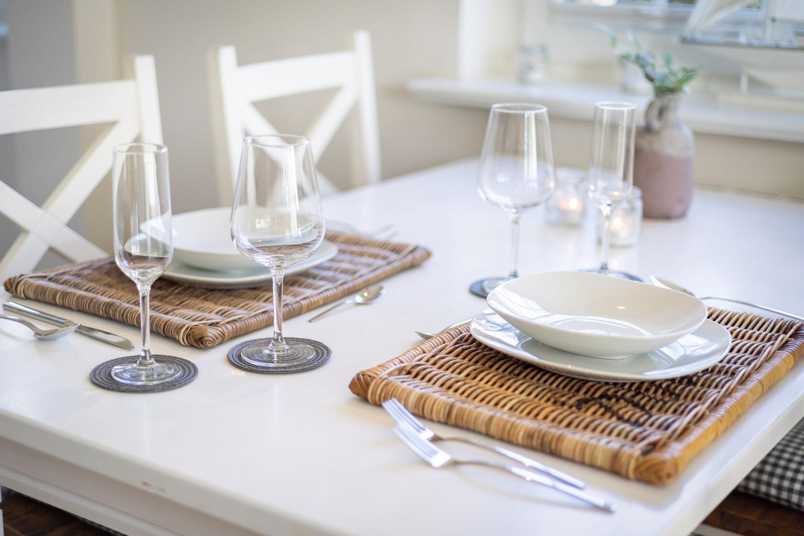Table set with plates, glasses, and cutlery on woven placemats.