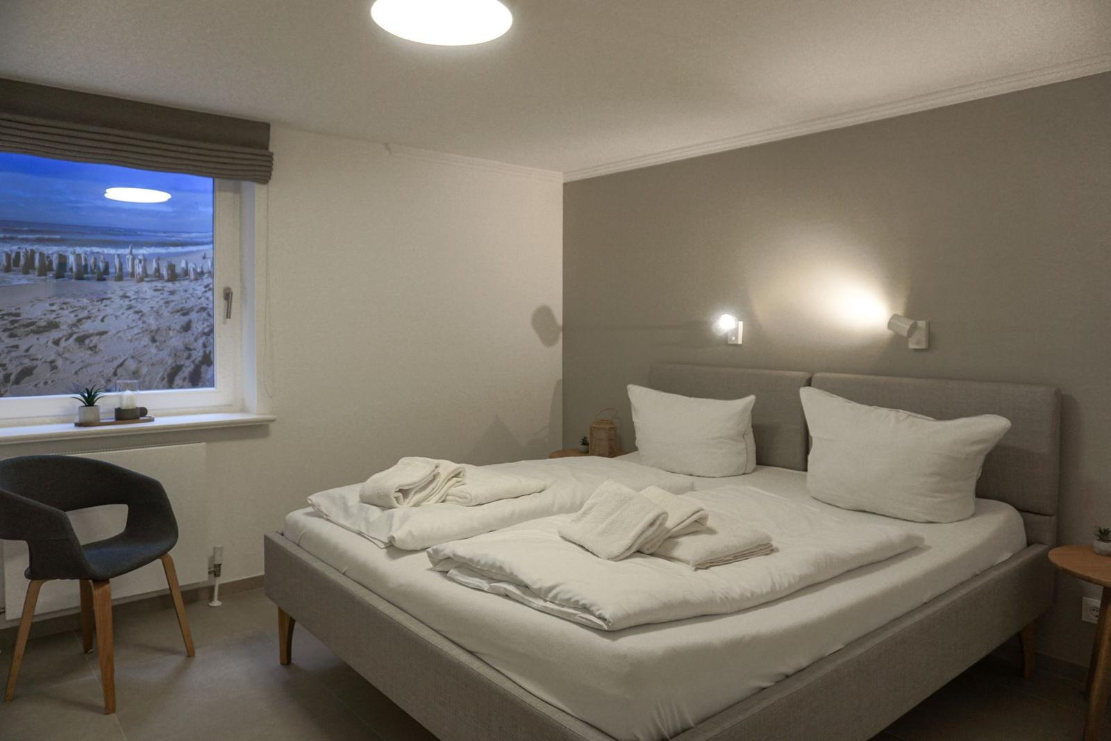 Schlafzimmer mit Bett, Fenster und Stuhl