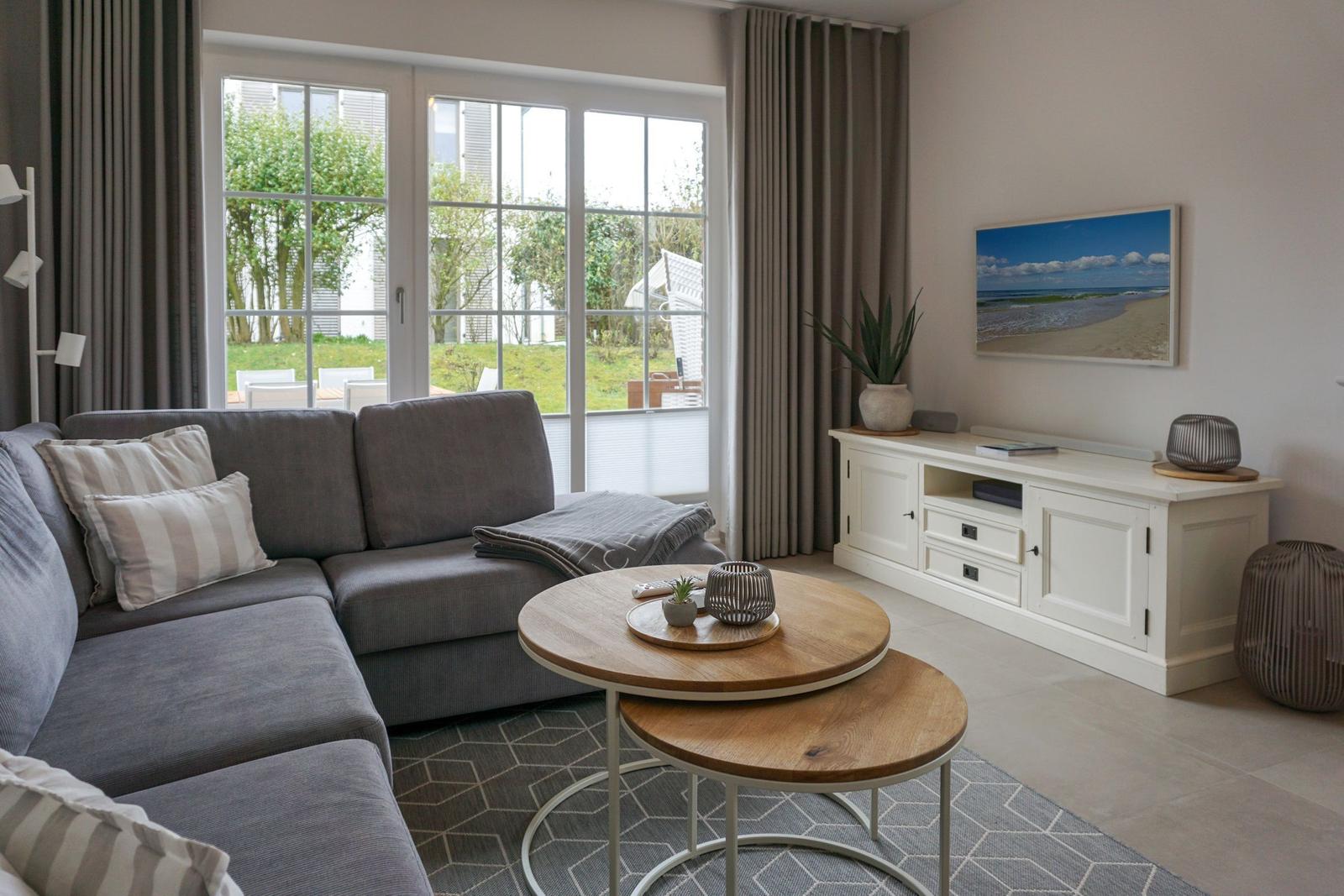 Wohnzimmer mit grauem Sofa, Holztisch und TV-Möbel.