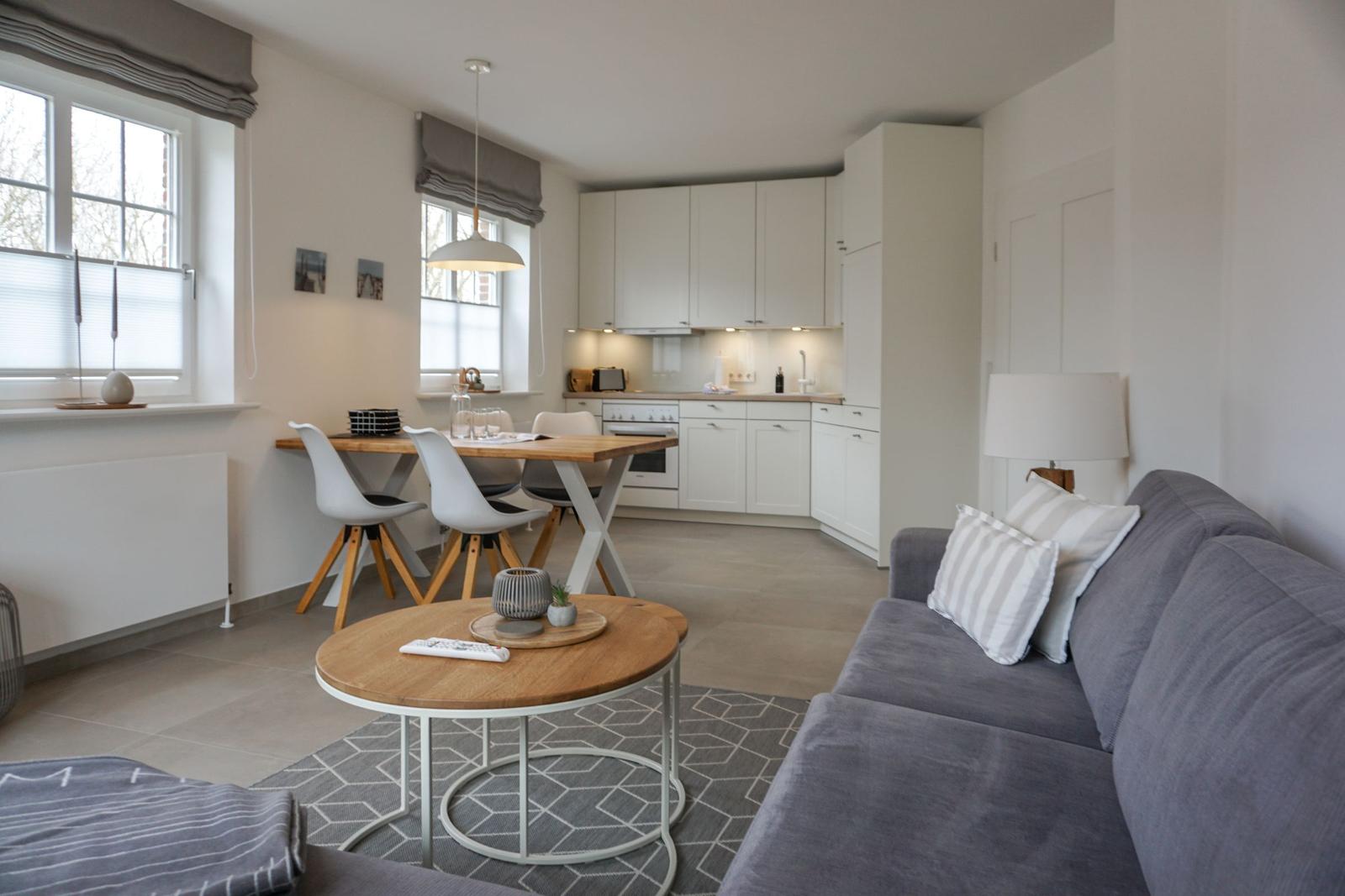 Wohnzimmer mit Sofa, Couchtisch und Essbereich. Küche im Hintergrund.