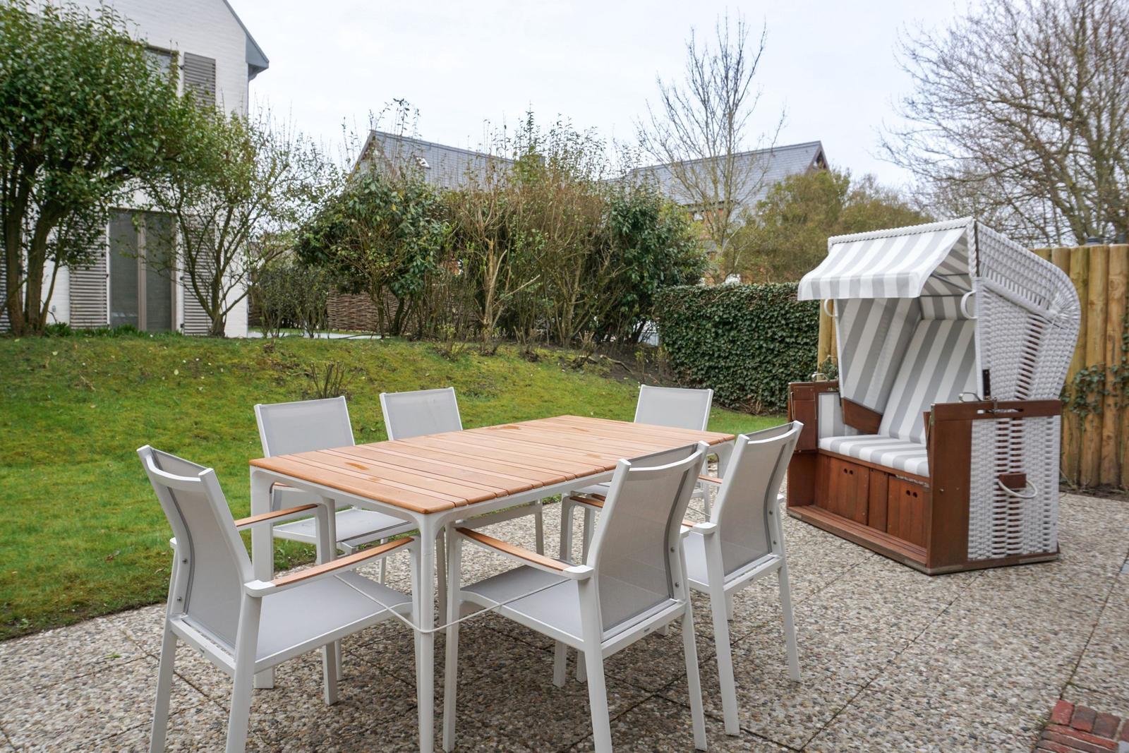 Hinterhof mit Tisch, sechs Stühlen und Strandkorb.