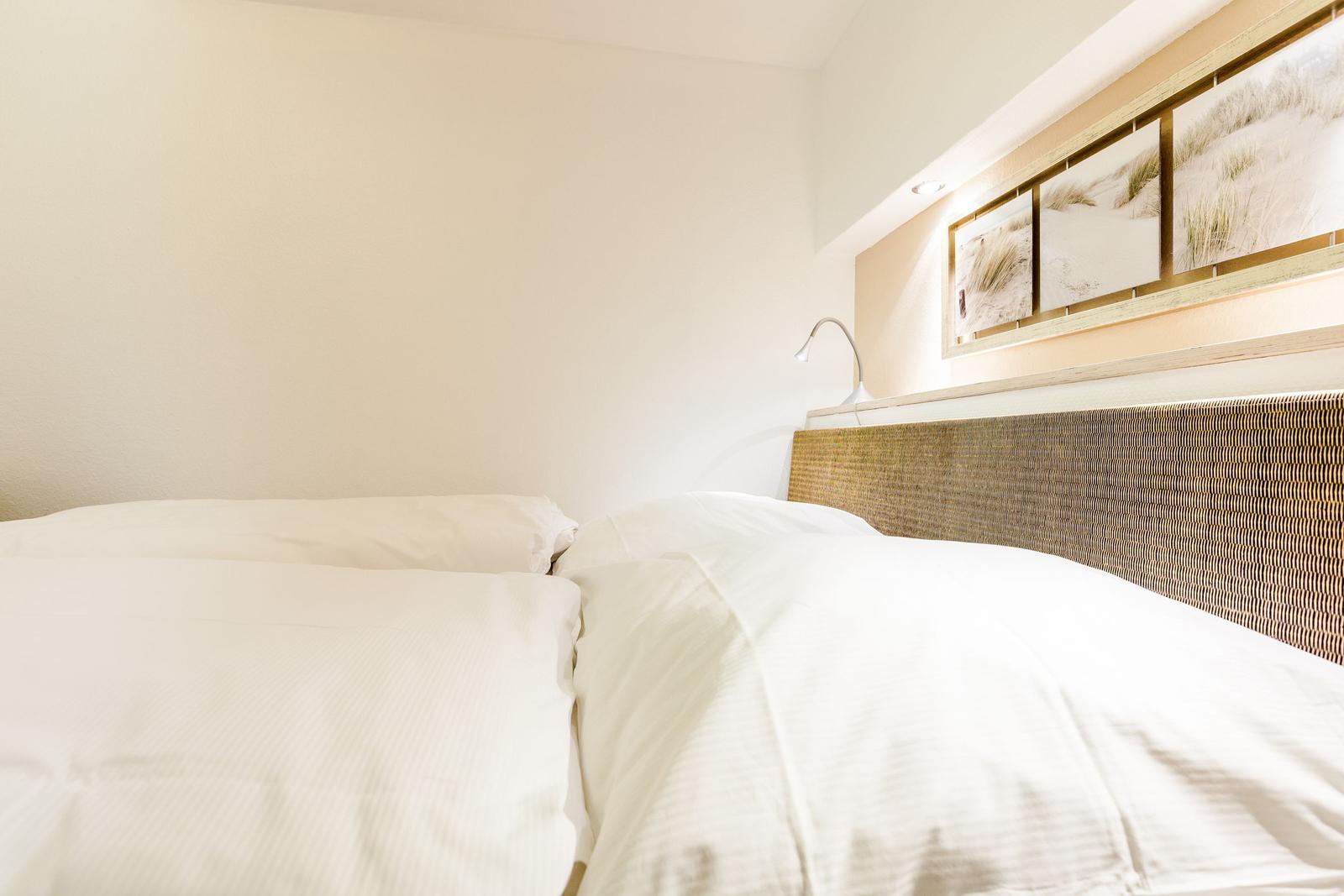 Double bed with white bedding and woven headboard