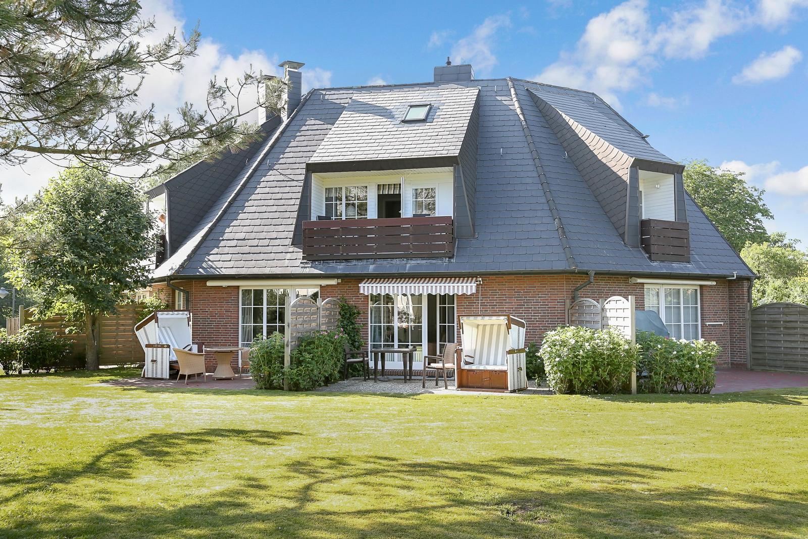 House with garden, terrace, and beach chairs. Roof with slate and wooden balcony.