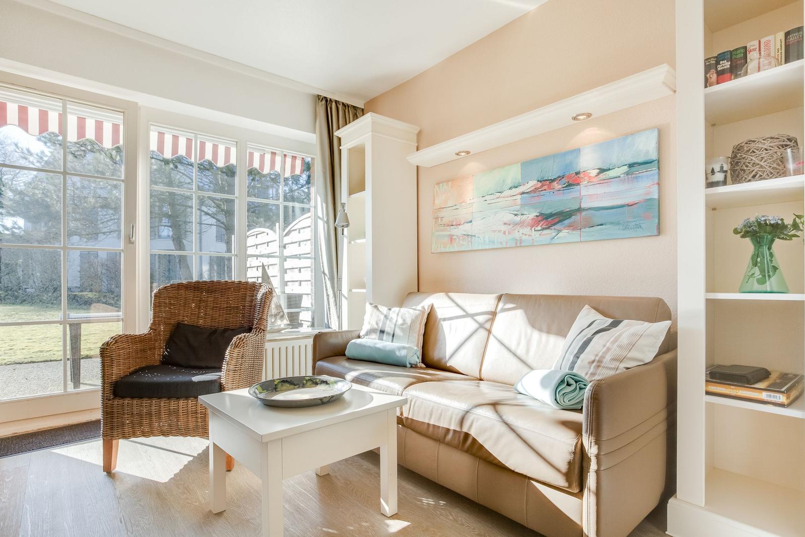 Living room with sofa, armchair, and windows to outdoor terrace.