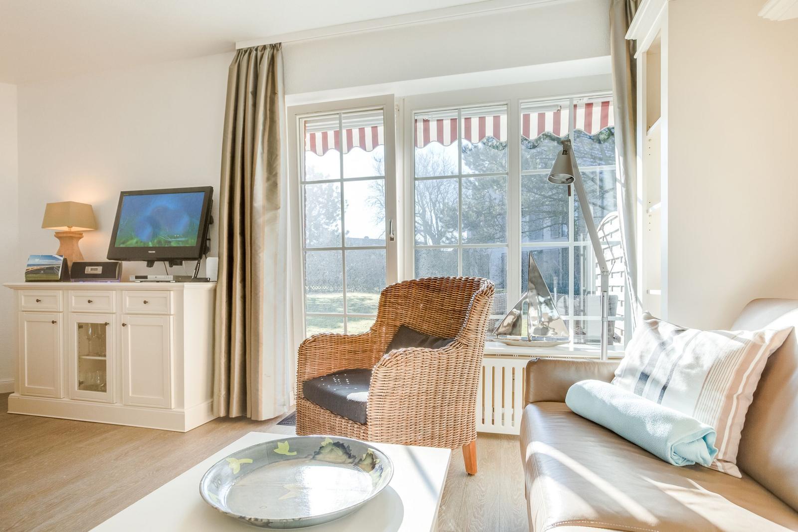 Living room with seating, TV, and windows overlooking the garden.