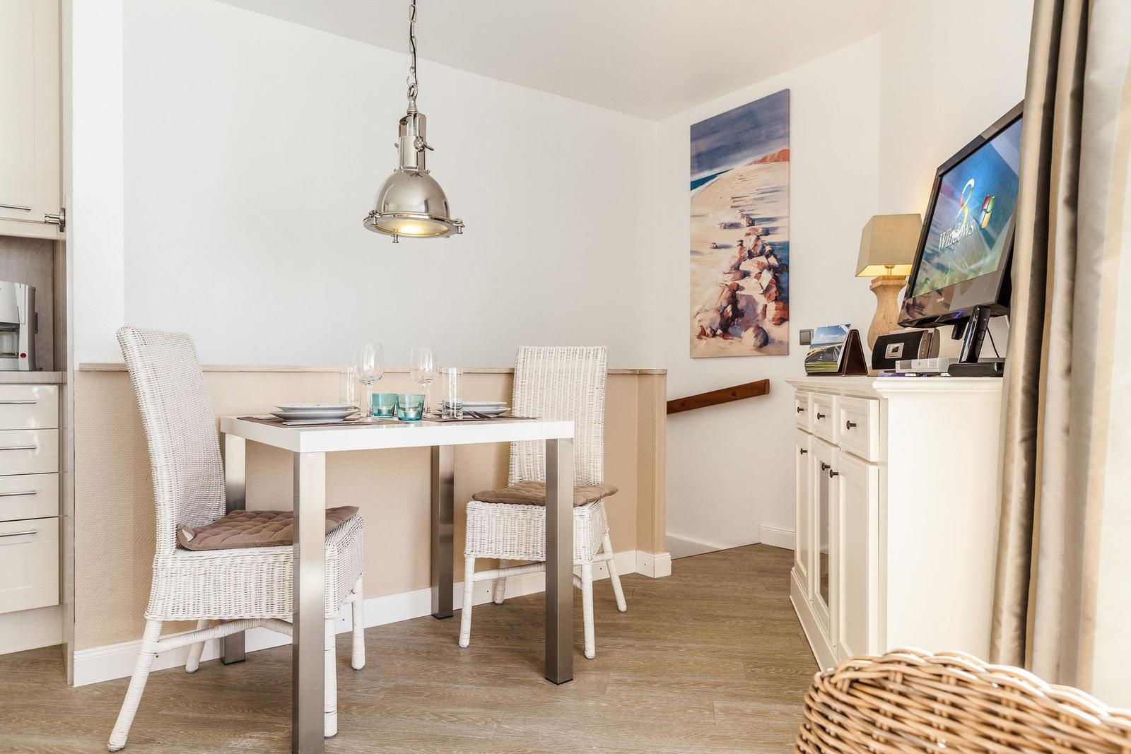 Dining area with table, two chairs, and wall art. TV on sideboard.