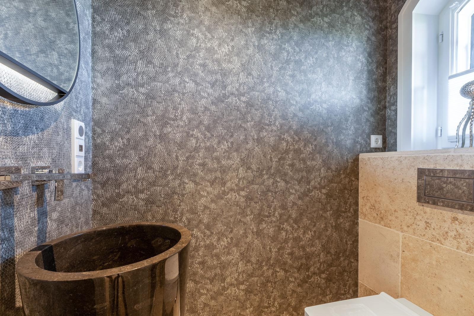Badezimmer mit Steinwaschbecken und texturierten Wänden.