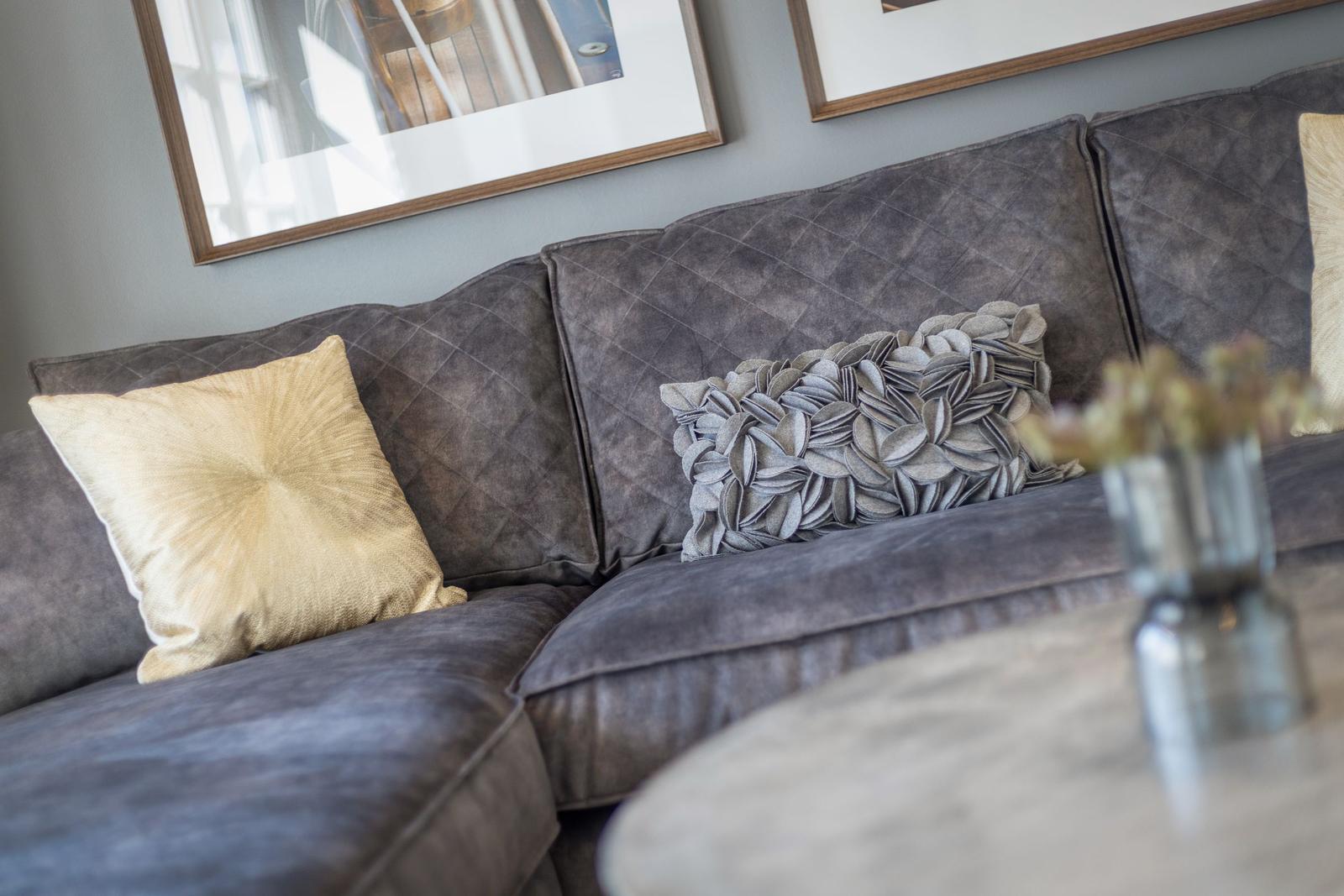 Grauer Sofa mit Kissen und Bildern an der Wand.