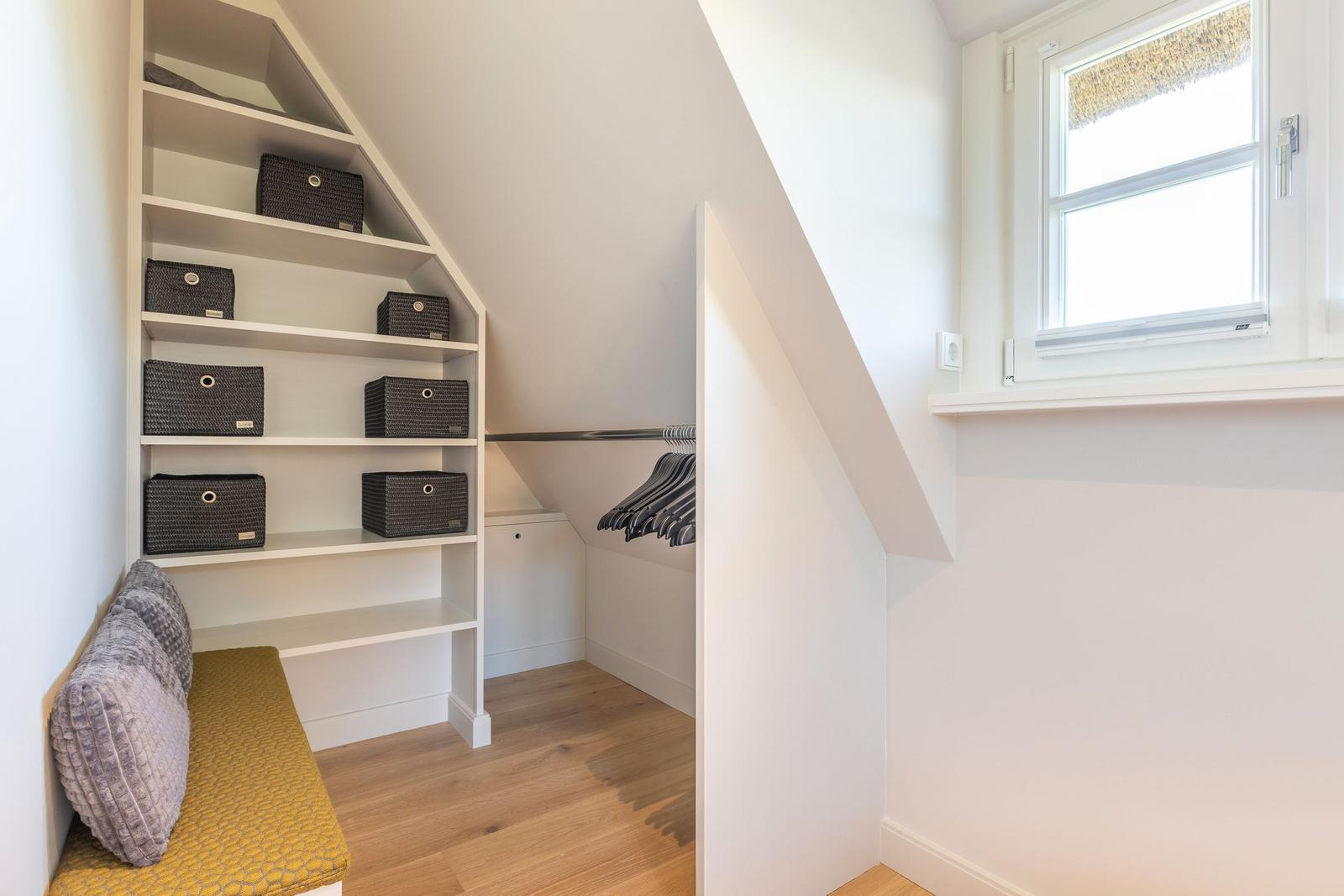 Schlafzimmer mit Dachschrägen, Kleiderschrank und Fenster.