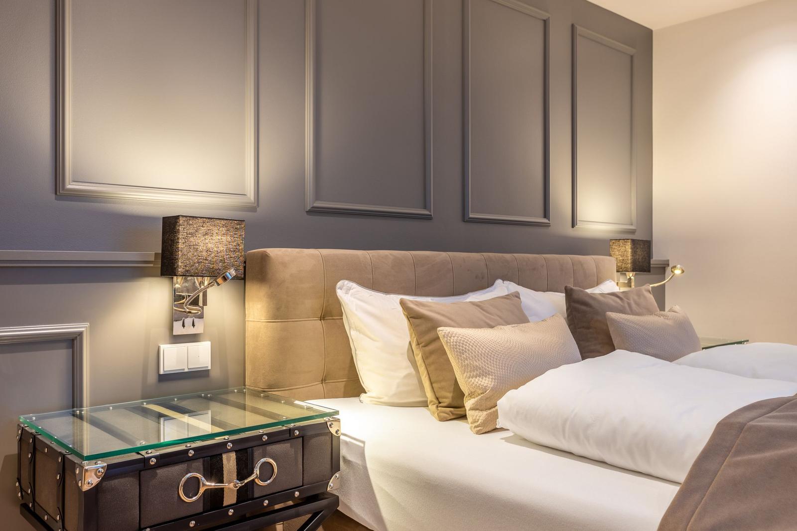 Schlafzimmer mit Bett, Kissen und Nachttisch mit Glasplatte.