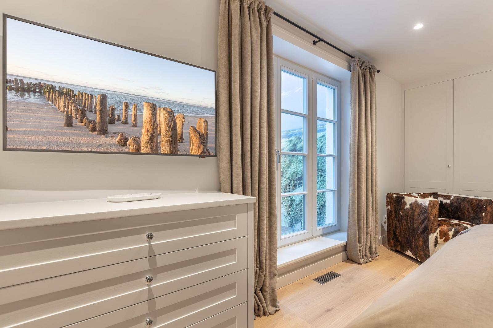 Schlafzimmer mit Fernseher, Fenster und Schrank.