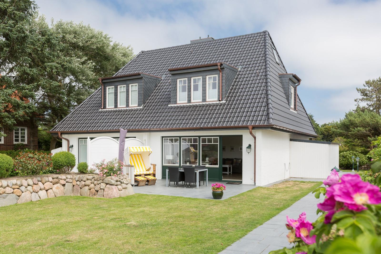 Wohnhaus mit Terrasse, Garten und Strandkorb.