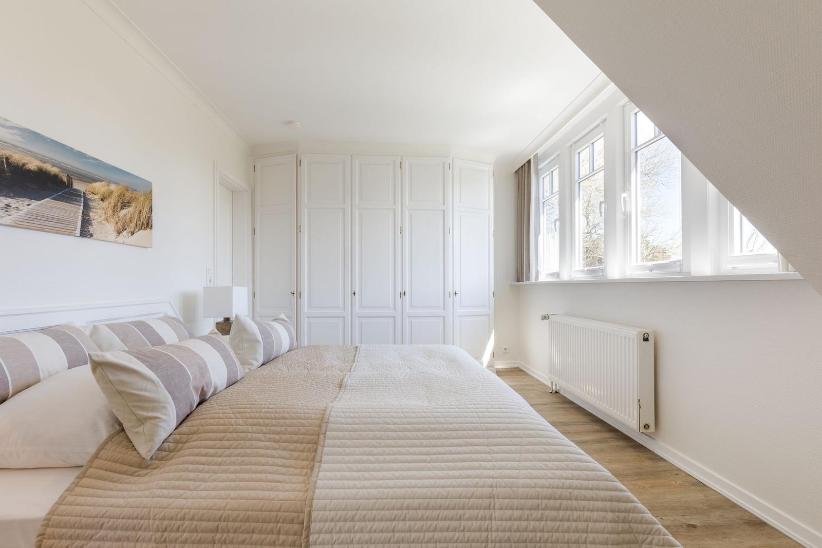 Schlafzimmer mit Bett, Kleiderschrank und Fenster