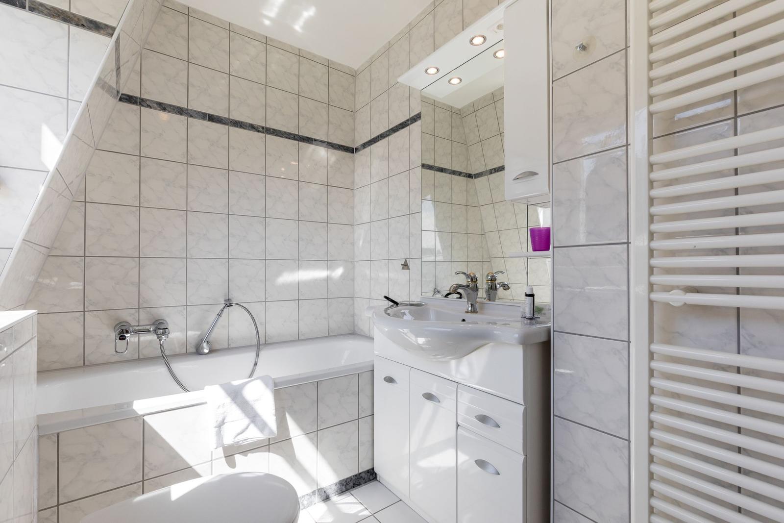 Badezimmer mit Badewanne, Waschbecken und Heizung.