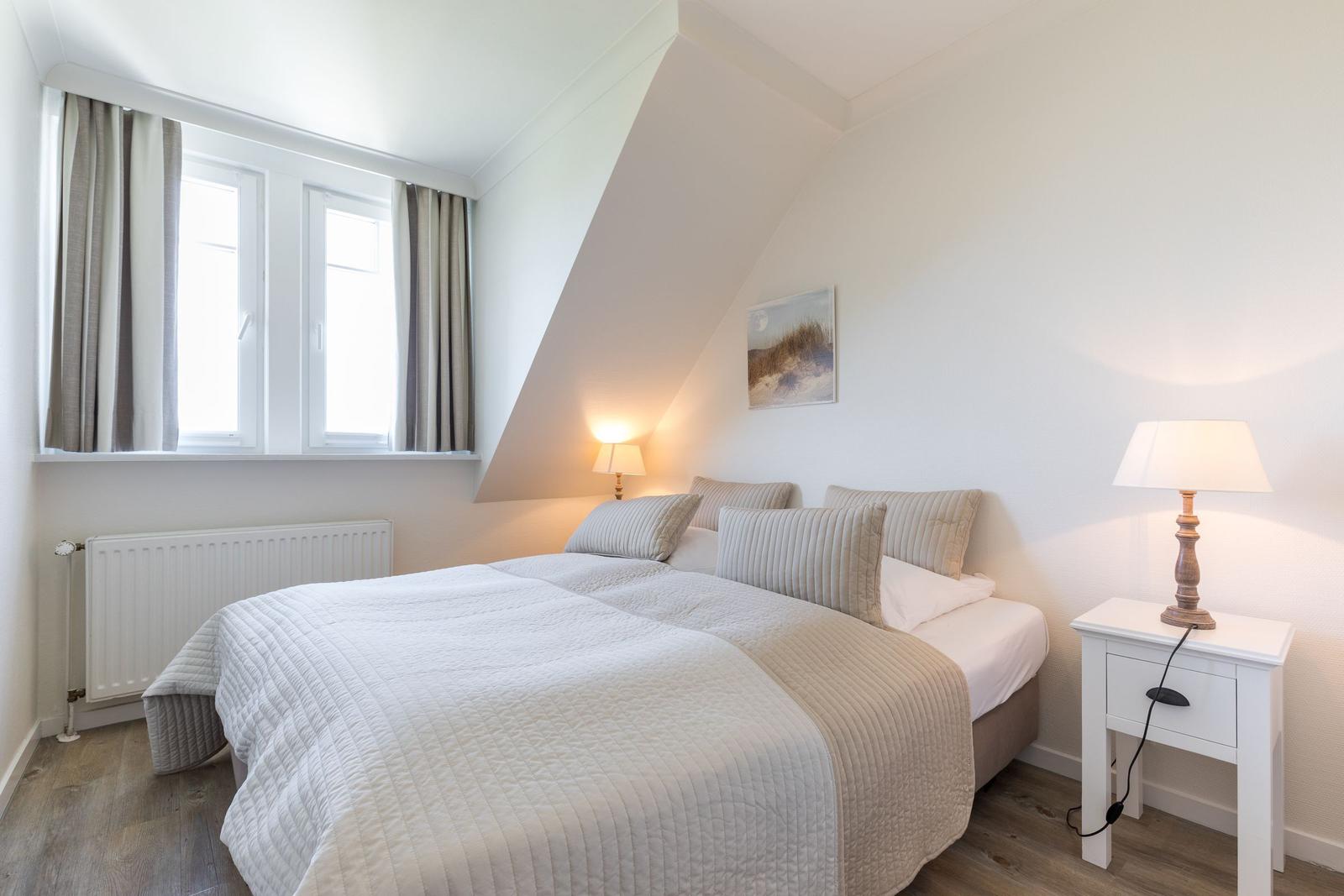 Schlafzimmer mit Dachschräge, Bett, Nachttisch und Fenster.