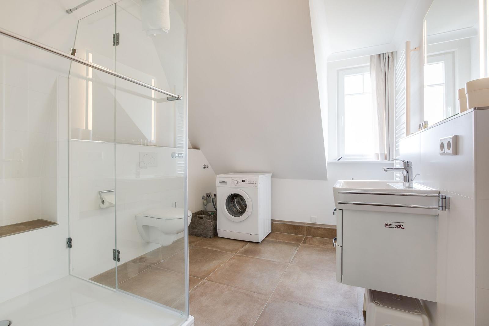 Badezimmer mit Dusche, Waschmaschine und Waschbecken