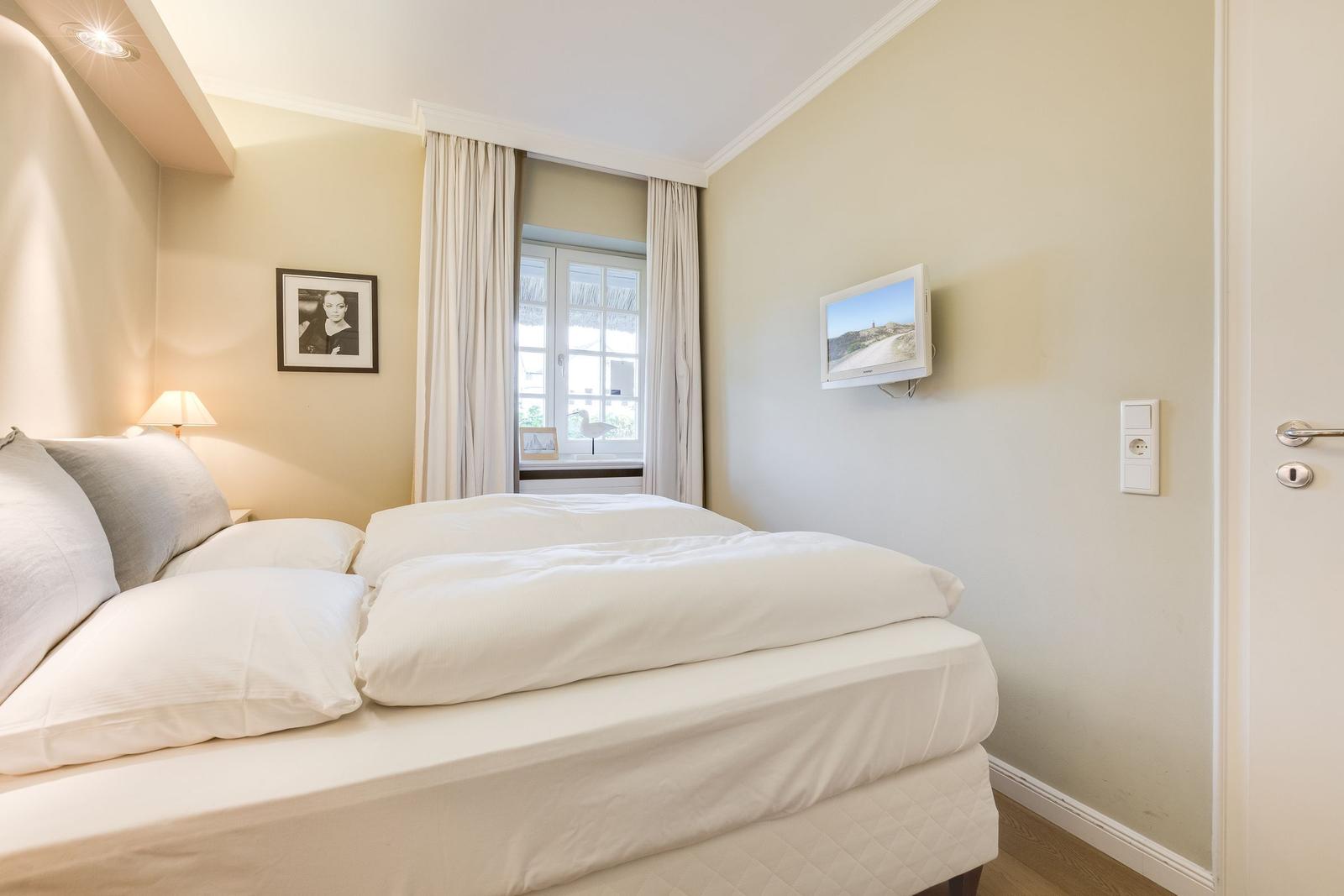 Bedroom with bed, window, and wall-mounted TV.