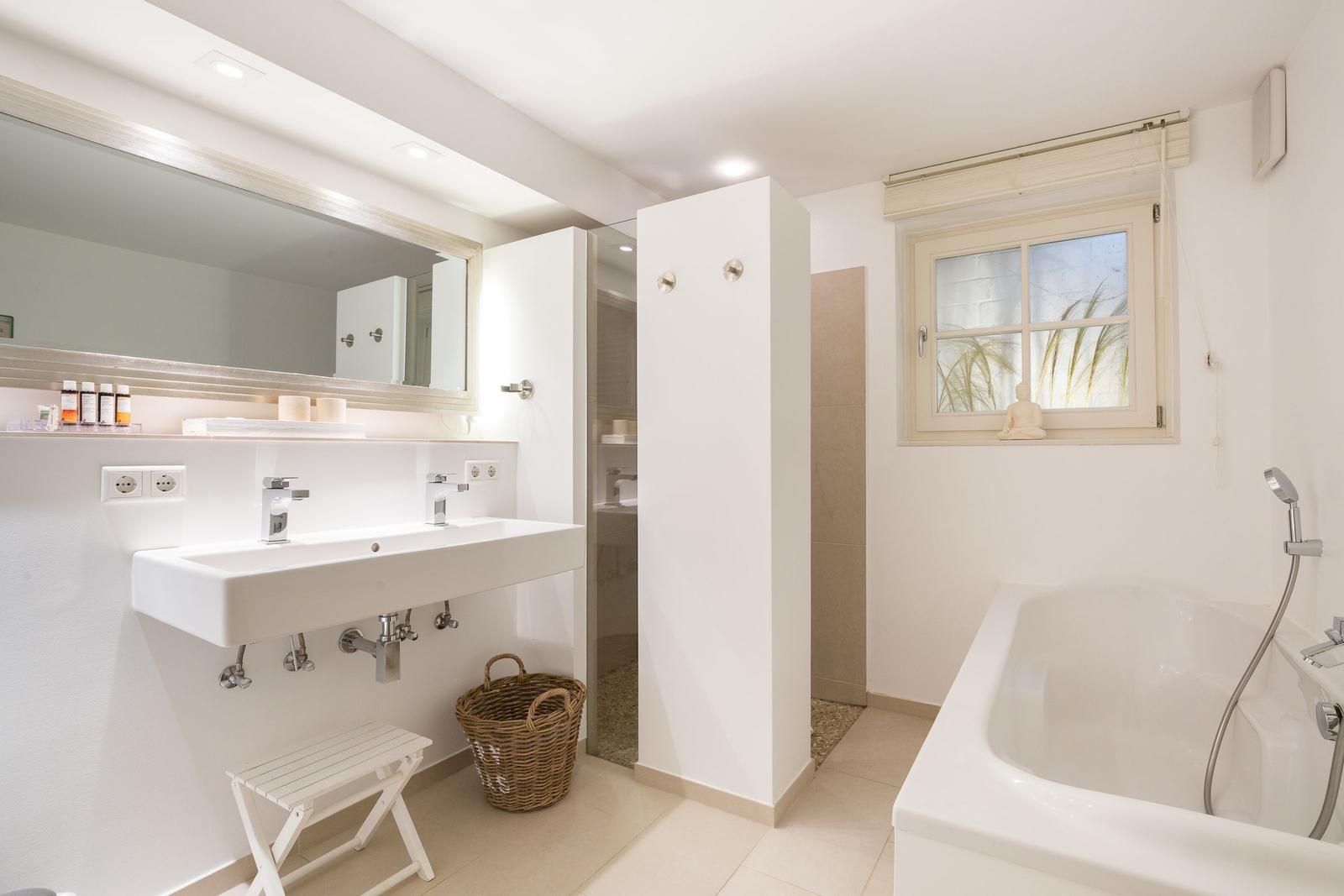 Bathroom with sink, shower, and bathtub. Window with view of grass.