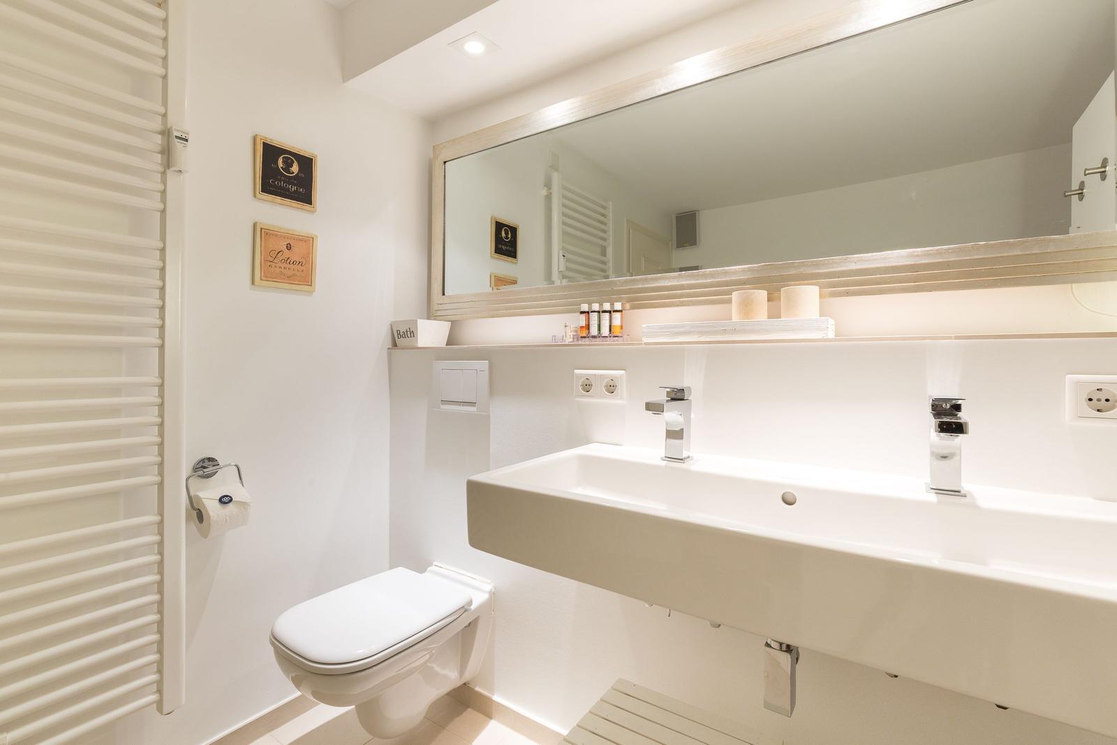 Bathroom with sink, mirror, and toilet. Warm lighting and wooden accents.