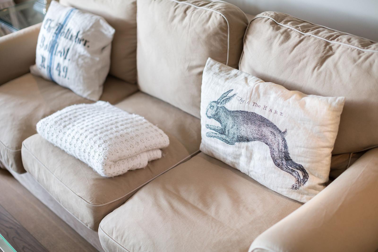 Beige sofa with cushions and knitted blanket