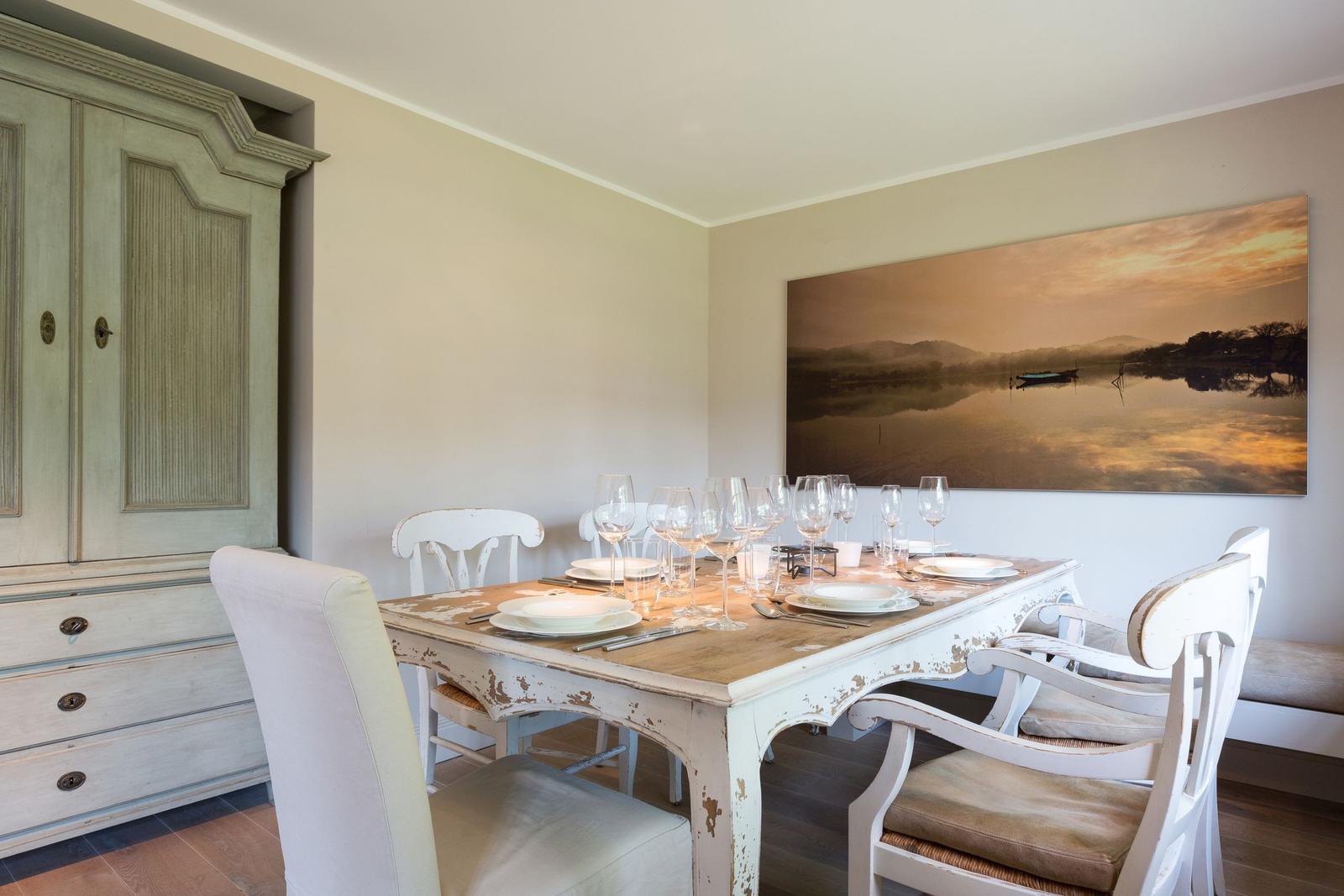Dining room with table, chairs, and wall art. Wooden cabinet against wall.