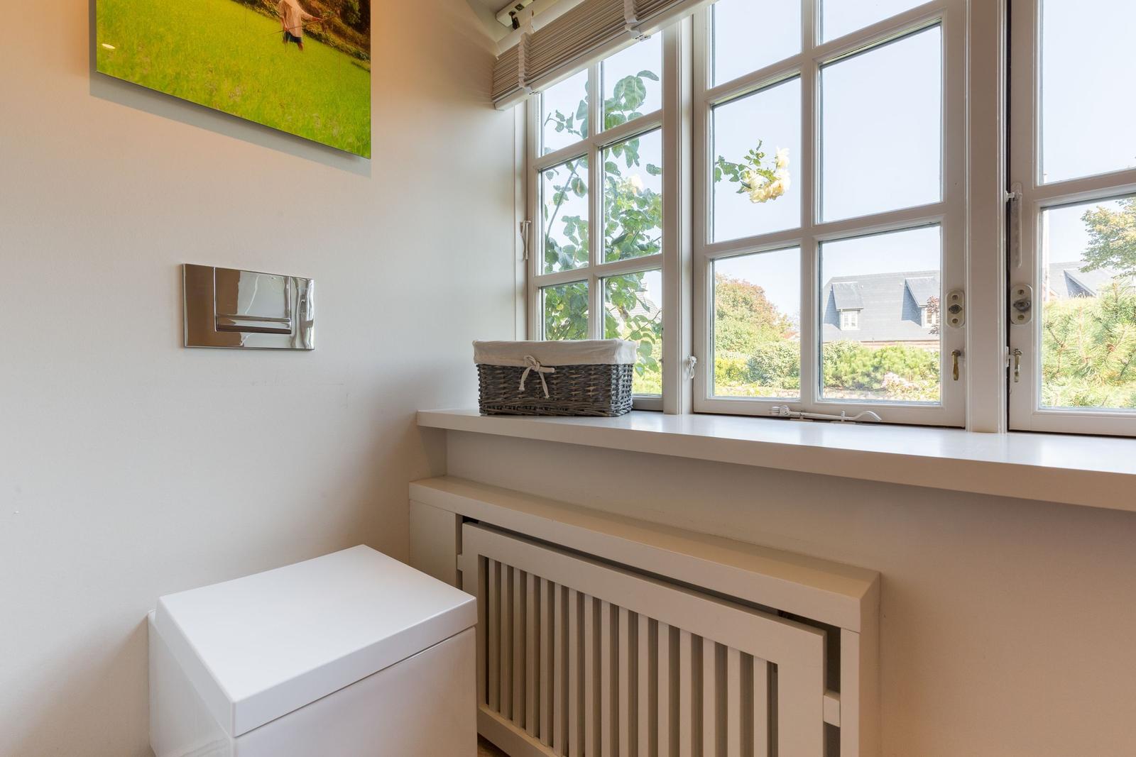 Bathroom with window, basket, and wall picture