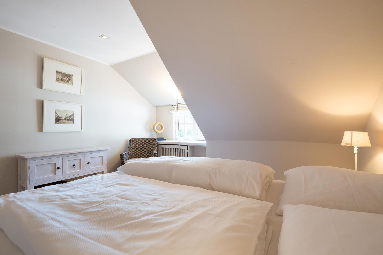 Room with two beds, window, lamp, and cabinet against the wall.