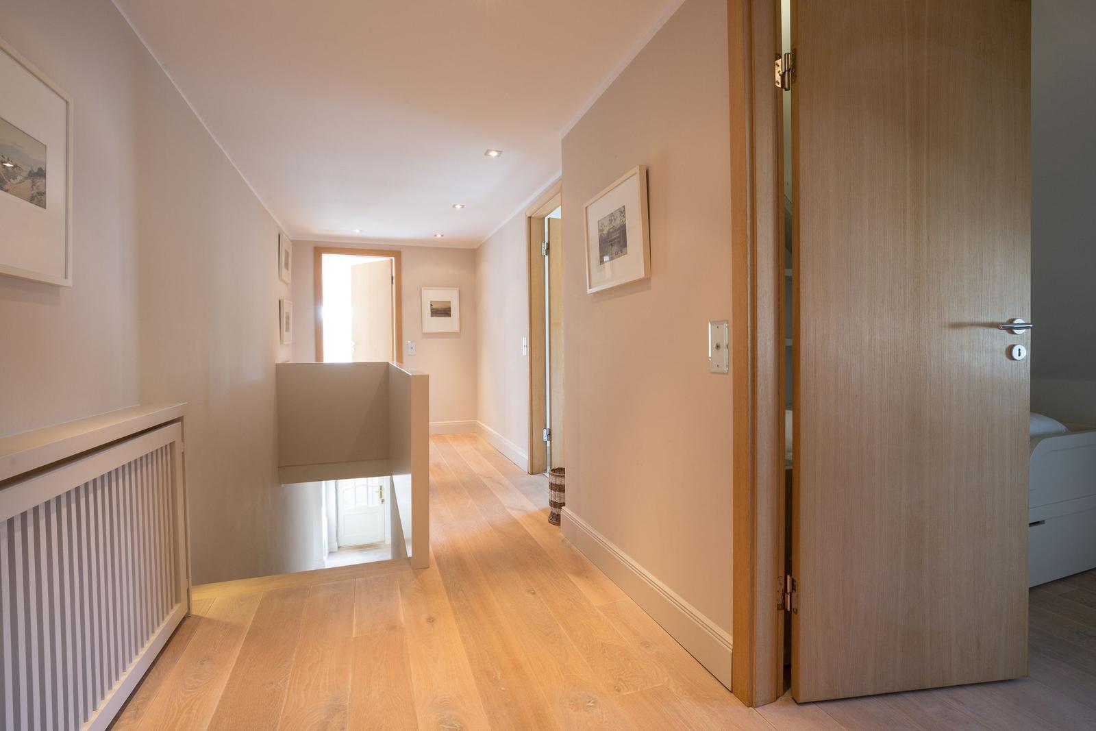 Hallway with wooden floor, doors, and wall pictures