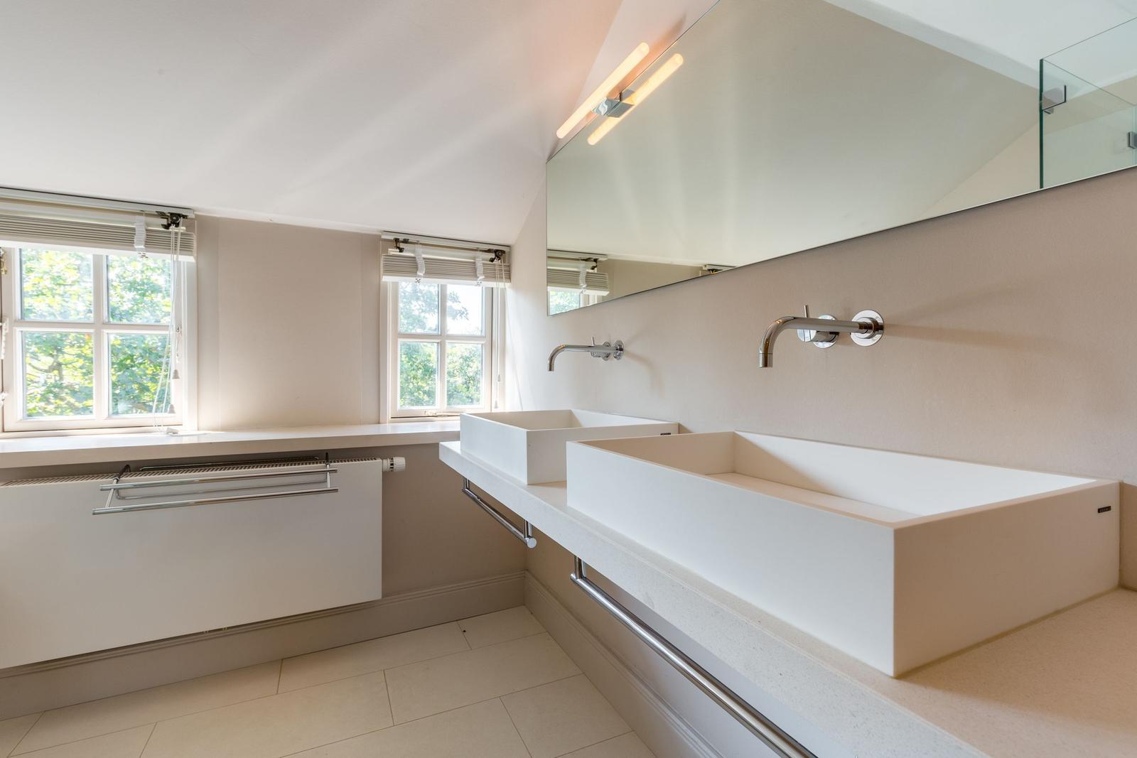 Bathroom with two sinks, mirrors, and windows