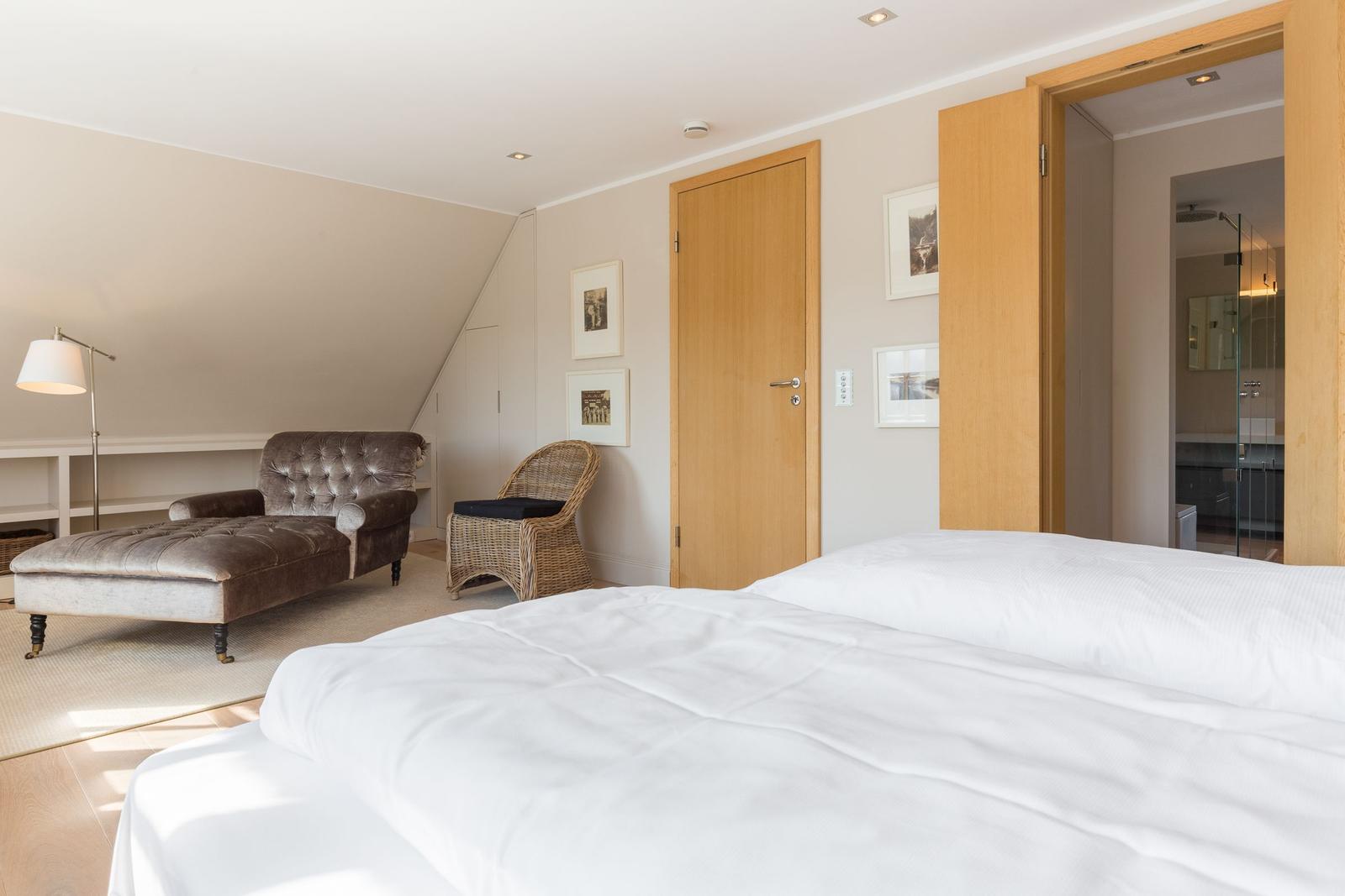 Bedroom with bed, chair, and view into the bathroom.