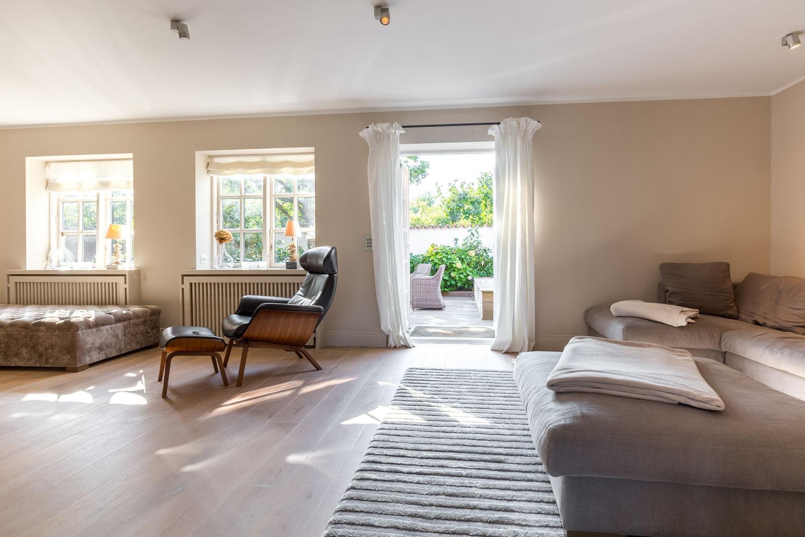 Living room with sofa, armchair, and view of the garden.