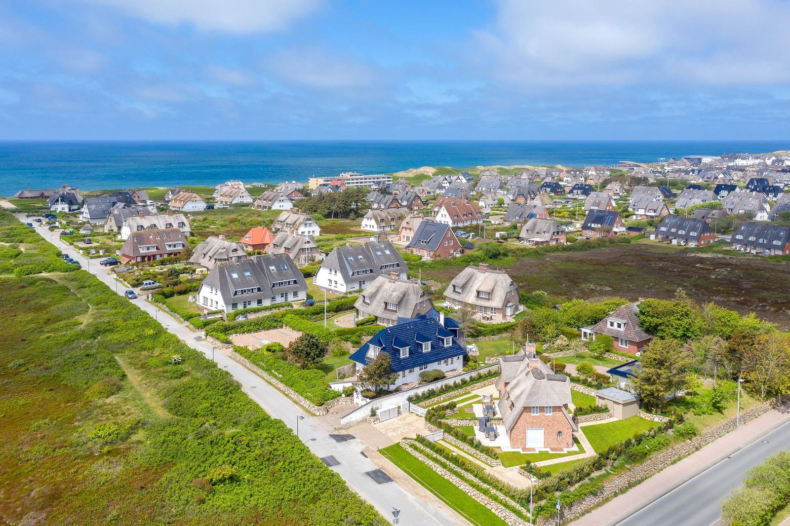 Aerial view of coastal village with traditional houses and ocean in background.