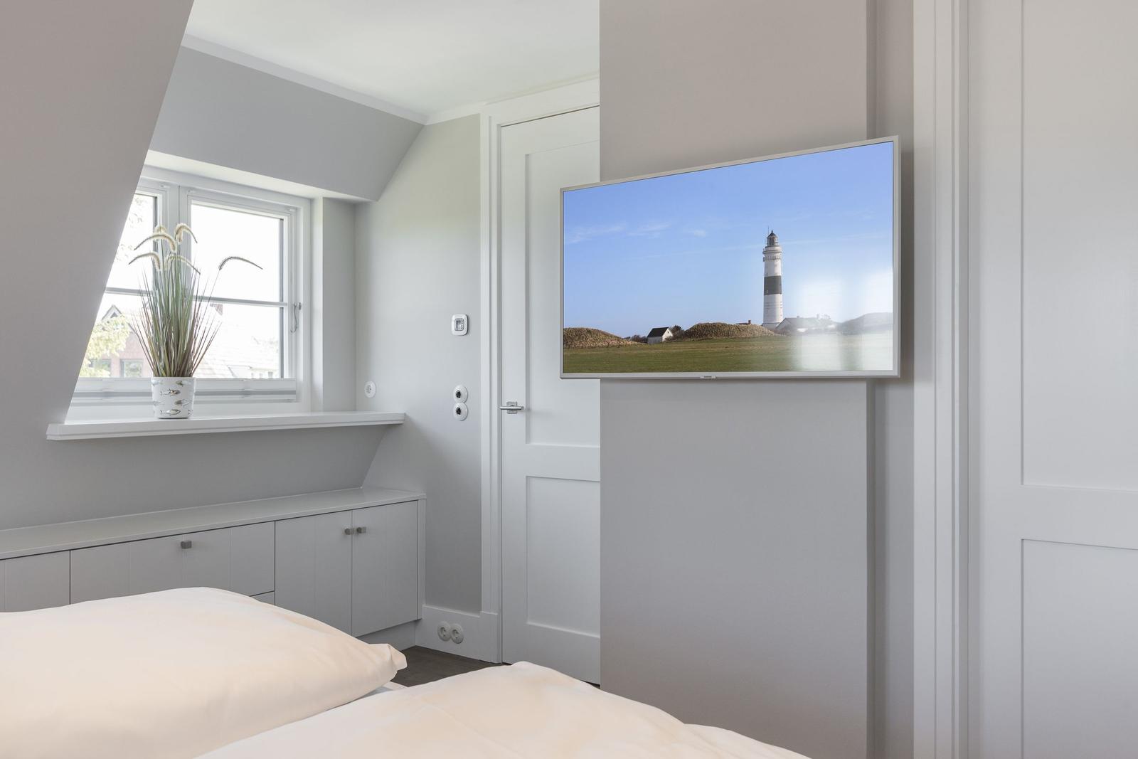 Schlafzimmer mit Bett, Fenster und Wandbild eines Leuchtturms.