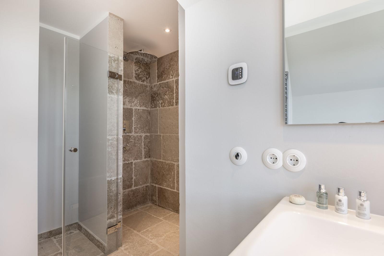 Dusche mit Steinwand, Waschbecken und Spiegel
