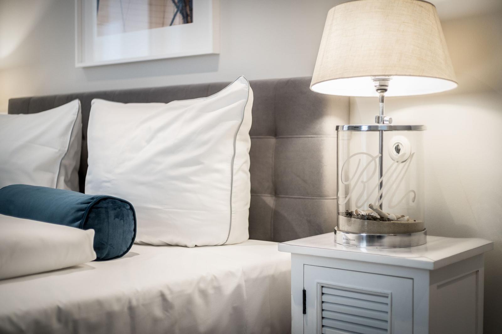 Schlafzimmer mit Bett, Kissen und Nachttisch mit Lampe.
