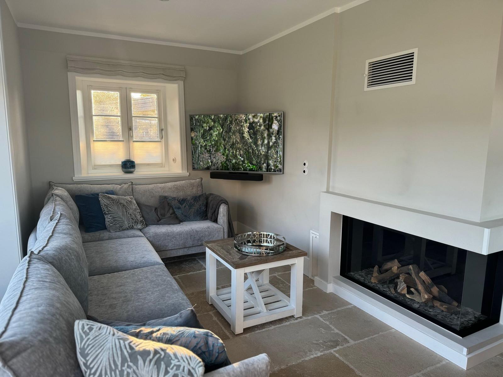 Wohnzimmer mit Sofa, Fernseher und Kamin
