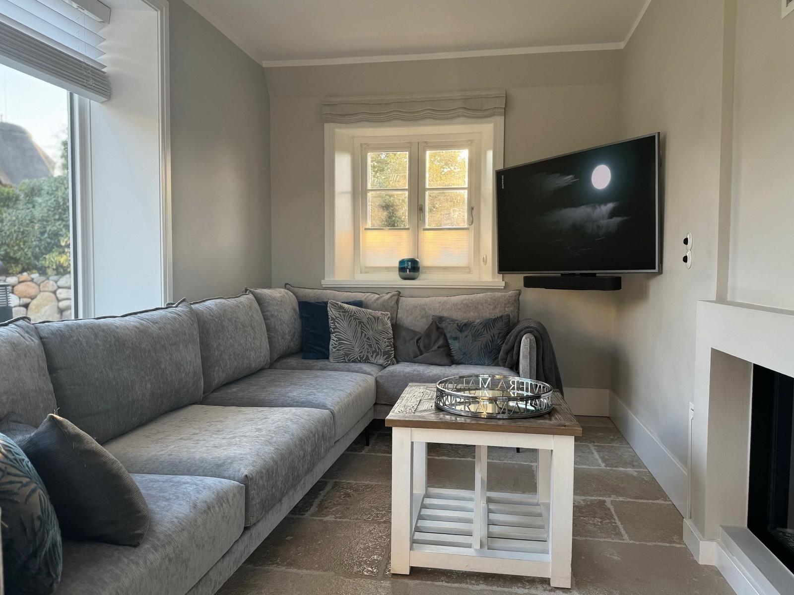 Graue Sofa-Ecke, Fernseher und Kamin im Wohnzimmer.