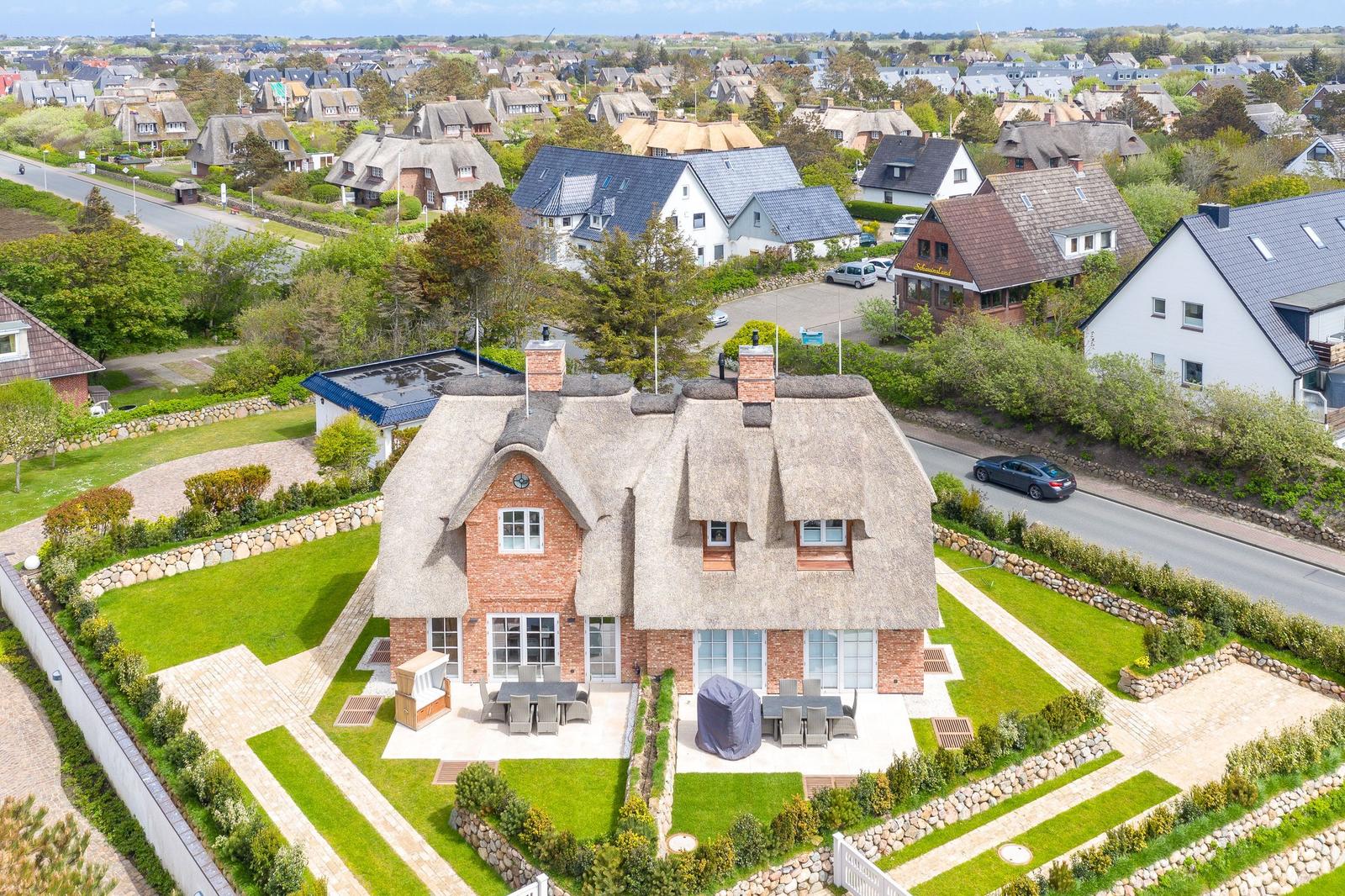 Haus mit Strohdach, Garten und Terrasse. Blick auf Wohnsiedlung.