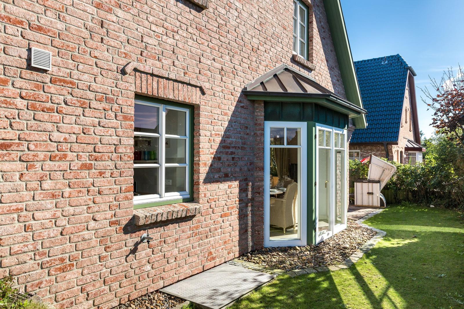 Rotes Backsteinhaus mit Fenster und Glasveranda im Garten.