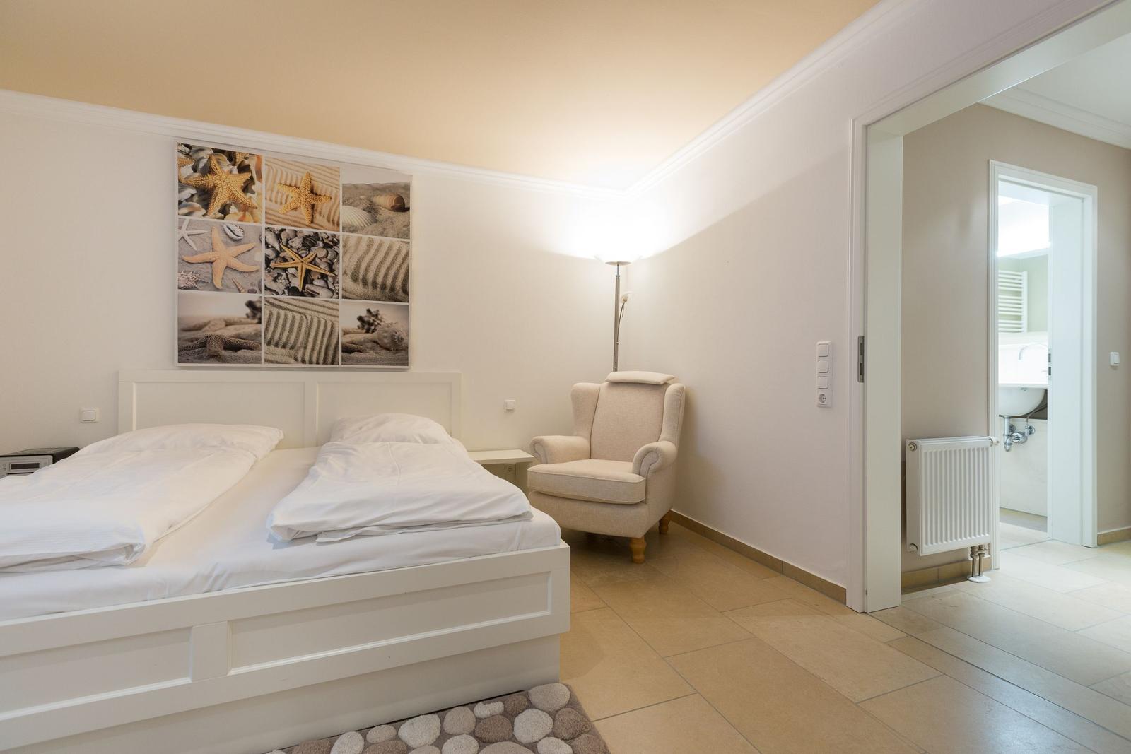 Schlafzimmer mit Doppelbett, Sessel und Badzugang