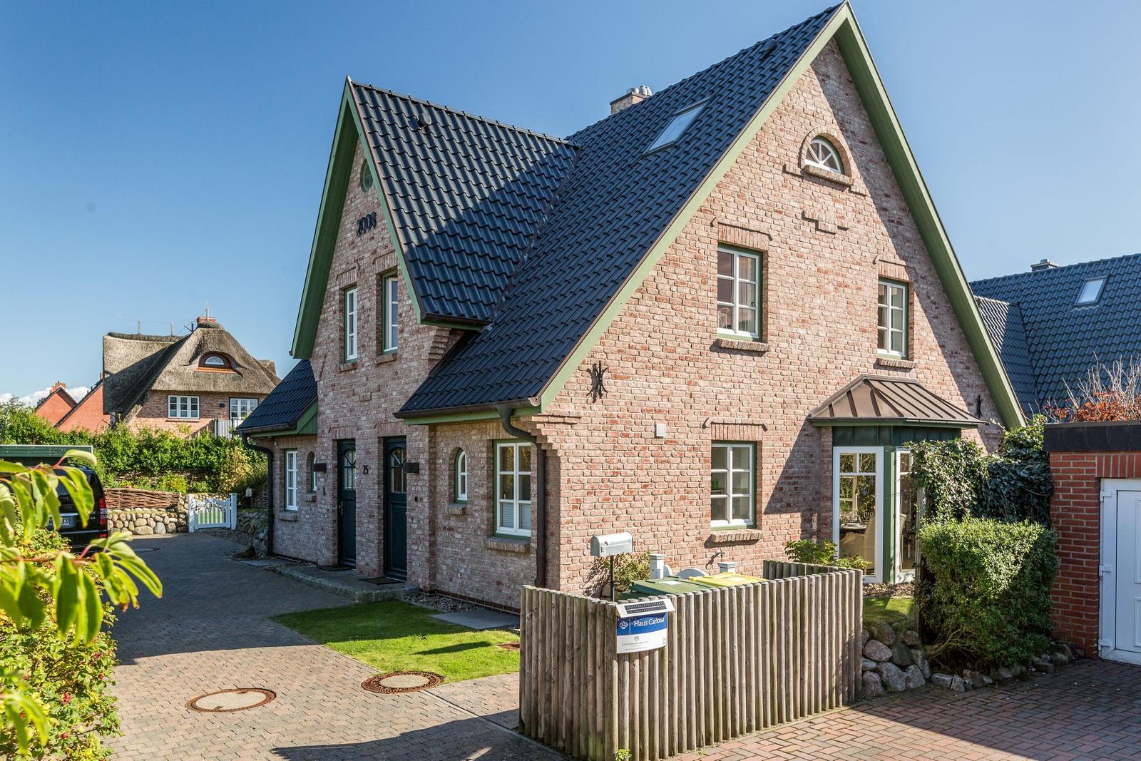 Ein zweistöckiges Backsteingebäude mit dunklem Dach und grünen Akzenten.