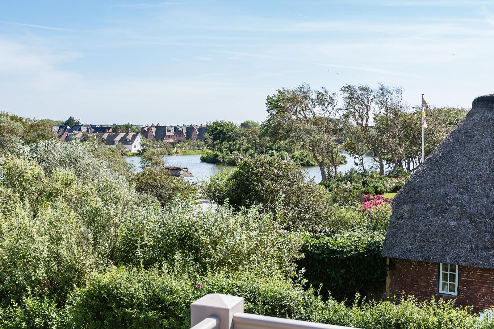 Peaceful view of river and houses with green vegetation and thatched-roof house.