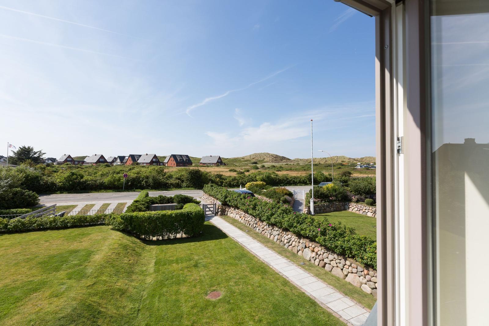 From the window, you can see a well-kept garden with stone path and holiday homes in the background.